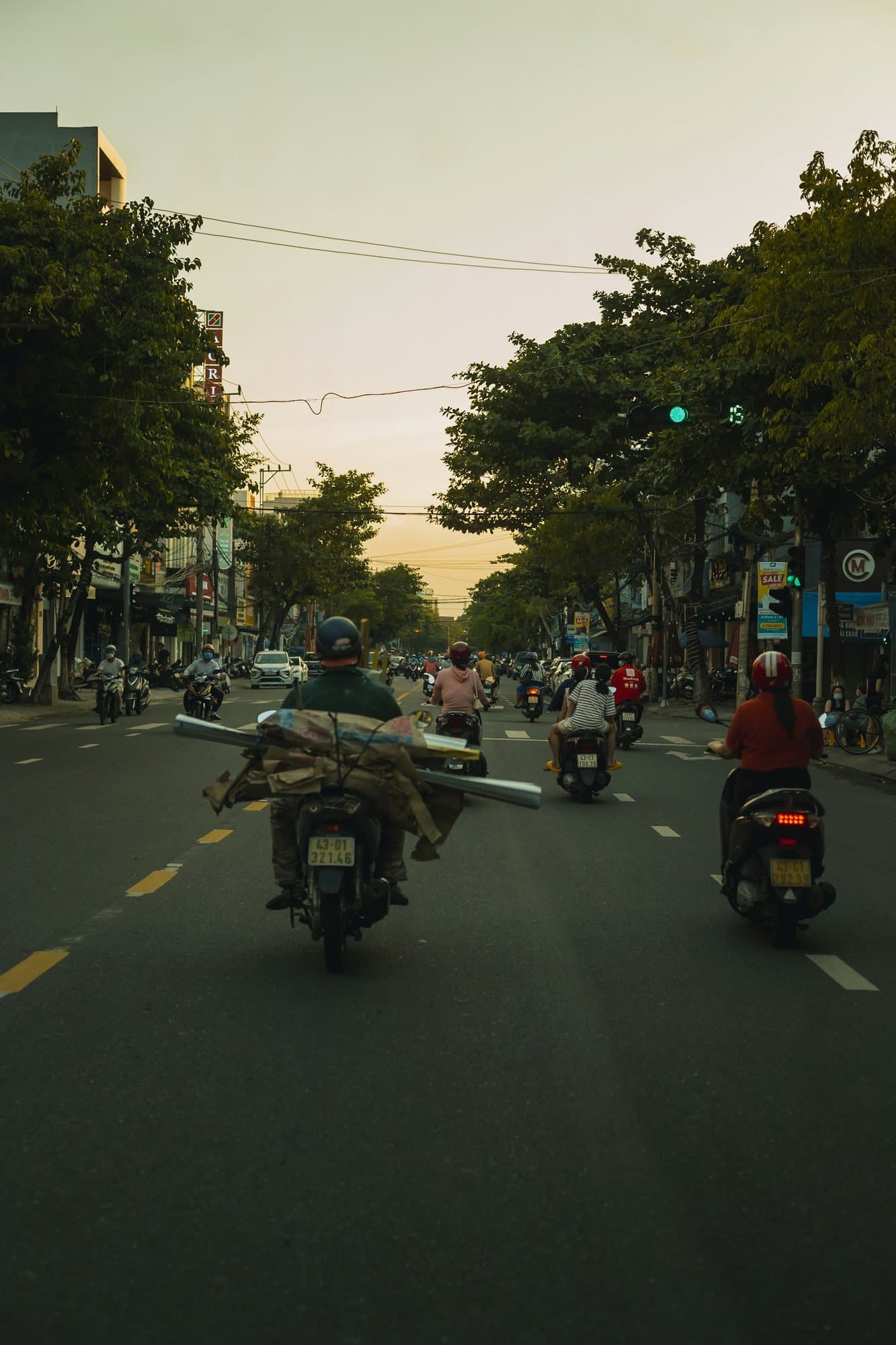 Everyday Da Nang street with scooters, trees, and shopfronts inland from the beach
