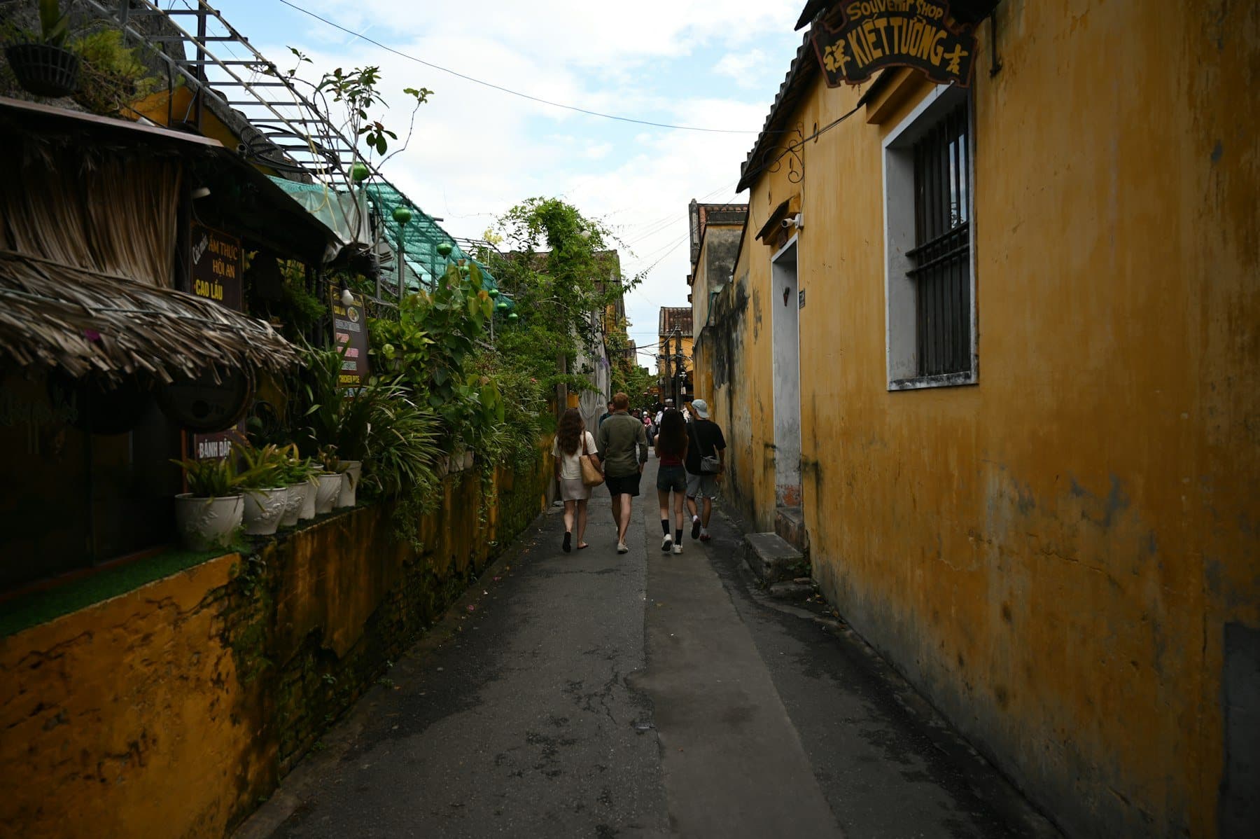Pedestrian alley in Hoi An Ancient Town with yellow walls and a cao lau stall