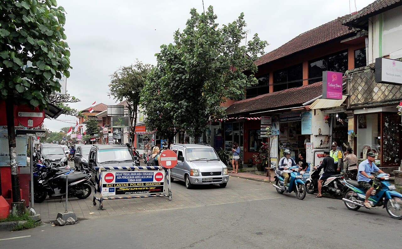 Ubud town street with scooters, shopfronts, and Balinese roofs